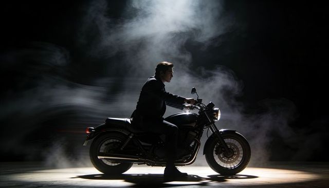 Moody dramatic motorcycle portrait posing man on cruiser in spotlight with swirling smoke