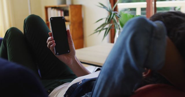 Person relaxing on couch holding smartphone at home - Download Free Stock Images Pikwizard.com