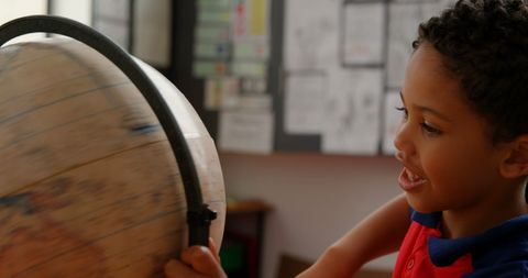 Curious Schoolboy Exploring World with Globe in Classroom