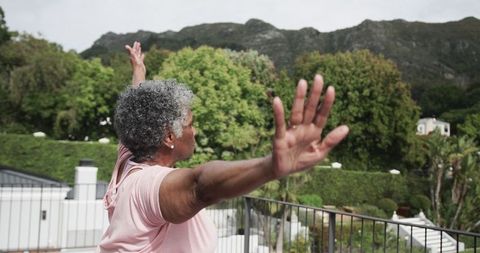 Senior woman practicing yoga outdoors on scenic balcony