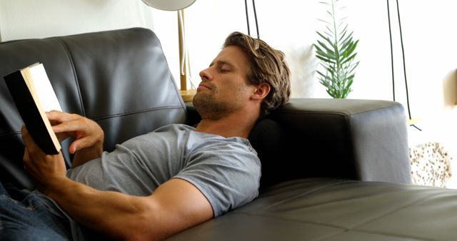 Young Man Relaxing on Leather Sofa While Reading Book - Download Free Stock Images Pikwizard.com