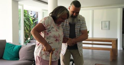 Senior man assisting woman with mobility in modern living space