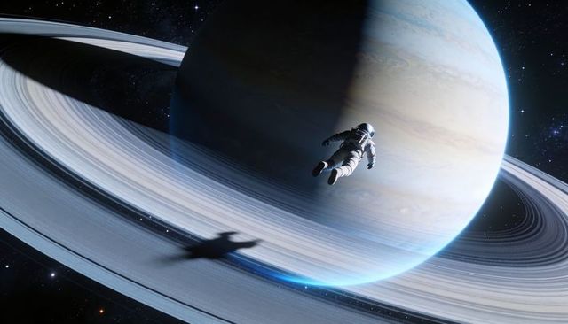 Solo astronaut drifting above icy rings of gas giant, reflective visor, dramatic shadow