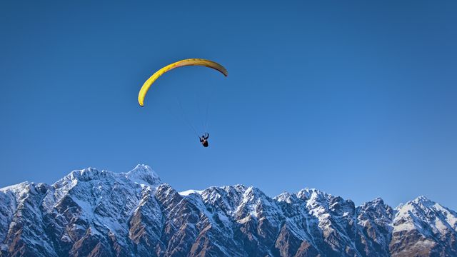 Yellow Paraglider Soaring Above Snowy Mountain Range in Clear Sky - Download Free Stock Photos Pikwizard.com