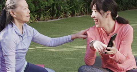 Mother and Daughter Sharing Tech on Outdoor Yoga Retreat