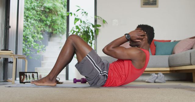 Happy african american man exercising in living room, using tablet - Download Free Stock Photos Pikwizard.com