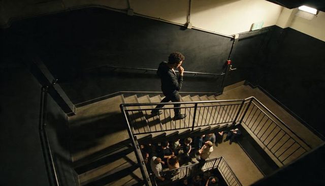 Man descending concrete stairwell above crowded landing dramatic overhead perspective