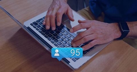 Typing Hands on Laptop with Social Notification 95 and Smartwatch on Wooden Desk
