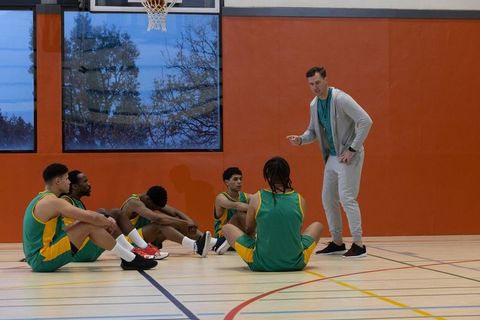 Coach motivating diverse basketball team on indoor gym court