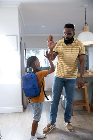 Father and son high-fiving at home entryway