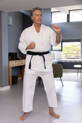 Senior Martial Artist Practicing Karate in Modern Living Room