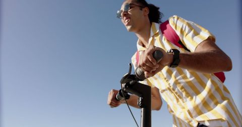 Joyful Man Enjoying Scooter Ride Under Clear Sky