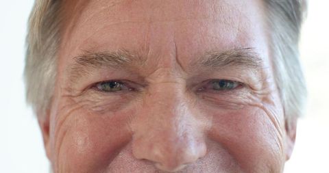 Close-up portrait of senior man smiling with light eyes and expressive facial wrinkles