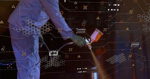 Industrial worker using spray gun with digital interface graphics