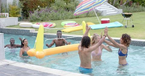 Diverse Group Enjoying Pool Volleyball Game on Sunny Day