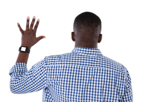 Man in checkered shirt and smartwatch raising hand, viewed from behind. Useful for concepts of communication, signaling, or casual fashion. Ideal for advertisements, presentations, or articles on technology, fashion, or body language.