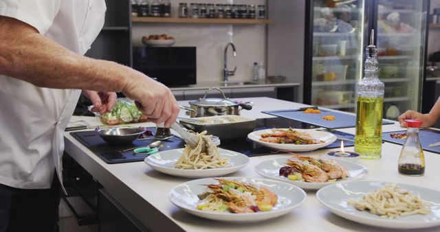 Shows a chef expertly plating multiple seafood pasta dishes in a professional kitchen. Ideal for illustrating culinary arts, gourmet dining, restaurant cuisine preparation, and cooking skills presentations. Useful for food magazines, cooking blogs, culinary training materials, and restaurant advertising.