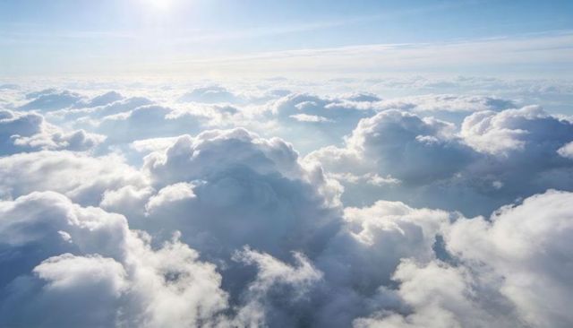 Sunlit cumulus sea floating above clouds, expansive aerial cloudscape with soft light