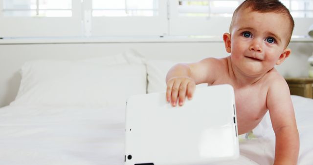 Cute baby holding a tablet on a bed - Download Free Stock Photos Pikwizard.com