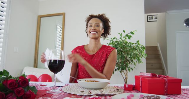 Woman celebrating Valentine's Day, enjoying dinner with a glass of wine. Gift boxes and flowers on the table add to the festive atmosphere, emphasizing romance and love. This image can be used for Valentine's Day promotions, greeting cards, advertisements for romantic occasions, or restaurant promotions.