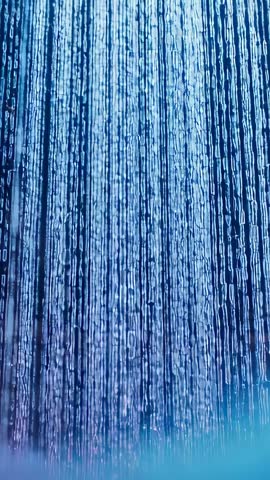 Vertical video recording teal water curtain falling, rippling, glowing fountain cascade