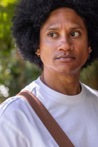 African american man looking left with nose ring and hoop earrings outdoor portrait