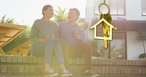 Happy couple celebrating new home ownership with coffee and gold key symbol