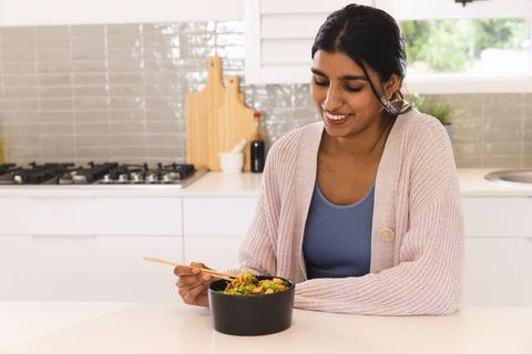 Smiling Woman Enjoying Healthy Meal in Modern Kitchen Area