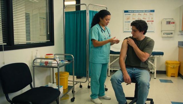 Nurse administering vaccination to young man in outpatient clinic for immunization and care