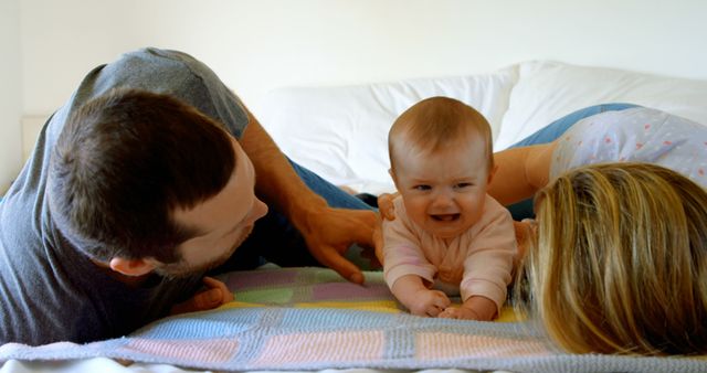 Parents showing emotions while comforting their crying baby on a bed with a colorful blanket. This can be used in materials about parenting, child development, family life, and emotional connection. Ideal for websites, magazines, advertisements, and social media campaigns focusing on family support, parental care, and home environment.