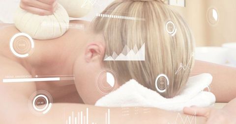 Blonde client receiving herbal compress with digital wellness hud overlays during spa massage