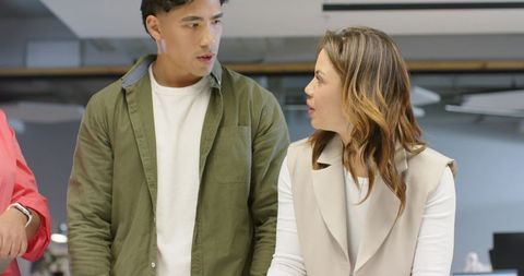 Diverse coworkers collaborating at open-plan workstation discussing project ideas