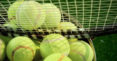 Basket of Yellow Tennis Balls Under Tennis Racket Imagery