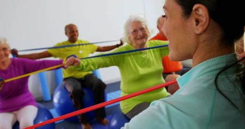 Senior group exercising on stability balls with instructor leading resistance-band routine