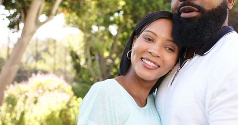 Diverse Couple Embracing in Sunlit Garden Showing Romance and Harmony