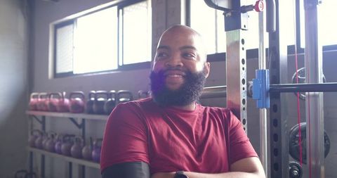 Smiling african man resting after strength training in industrial gym with kettlebells