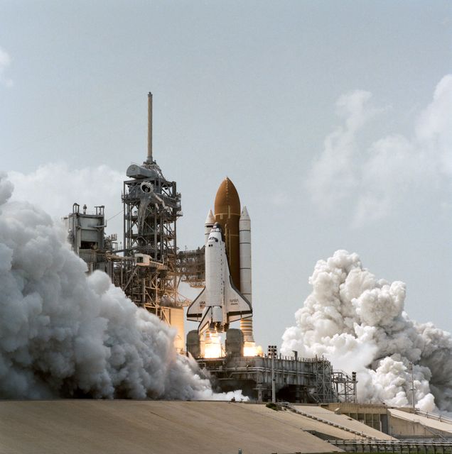 This image captures the dramatic moment when Space Shuttle Atlantis, carrying five NASA astronauts and two Russian cosmonauts, launches from Kennedy Space Center's Launch Pad 39A on June 27, 1995. This mission marks the 100th United States human space launch and aims to unite with the Mir Space Station crew in orbit. The scene is filled with billowing smoke and powerful thrust, epitomizing human achievement in space exploration. Ideal for content on space history, technology, and collaboration between nations in space endeavors.