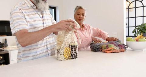 Eco-friendly senior couple arranging groceries with reusable mesh bags