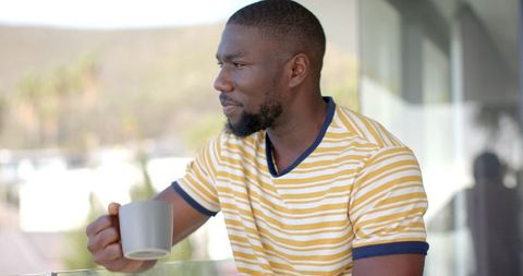 Thinking African American Man Holding Cofffee Cup on Modern Balcony