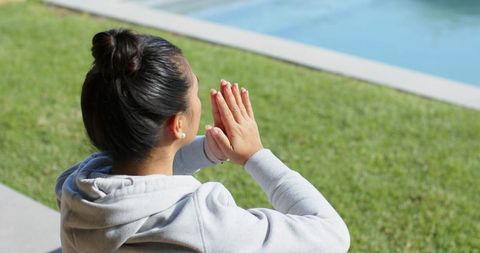 Woman Practicing Peaceful Yoga by Pool in Tranquil Outdoors