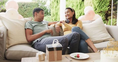 Young Couple Celebrating on Patio with Gifts and Cake