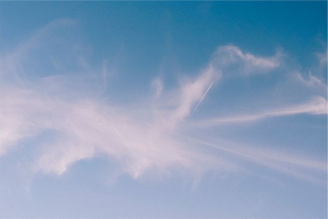 This image is perfect for backgrounds, nature-themed projects, or concepts emphasizing peace and tranquility. The clear blue sky with wispy clouds and visible contrails can be used in websites, presentation slides, and graphic design to evoke a sense of calm and spaciousness.