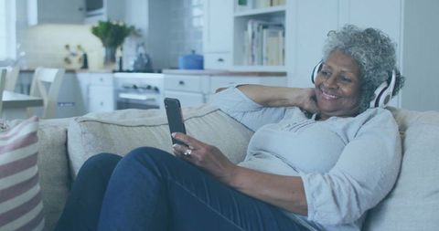Senior Woman Relaxing with Headphones and Smartphone at Home