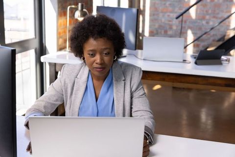 Focused woman working on laptop in modern office interior