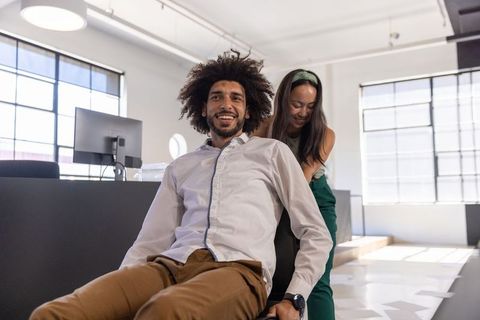 Diverse coworkers enjoy office fun in open workspace