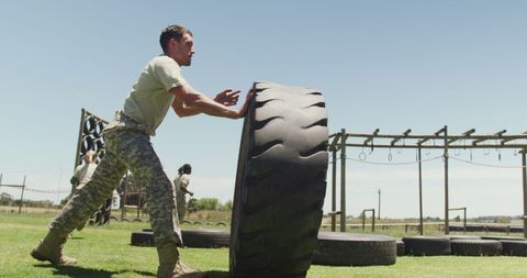 Soldier Flipping Tire on Obstacle Course Outdoors