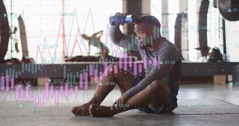 Male athlete resting on gym floor holding water bottle with fitness data overlay