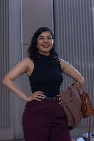 Confident professional woman posing in sleeveless black top and maroon trousers