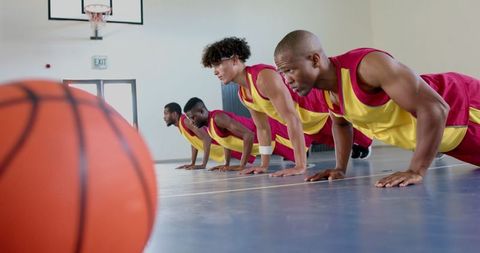 Diverse Basketball Team Building Strength with Push-Ups in Gym