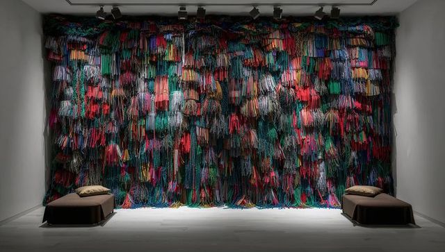 Showcasing multicolor textile wall installation with dense yarn fringe and tassels